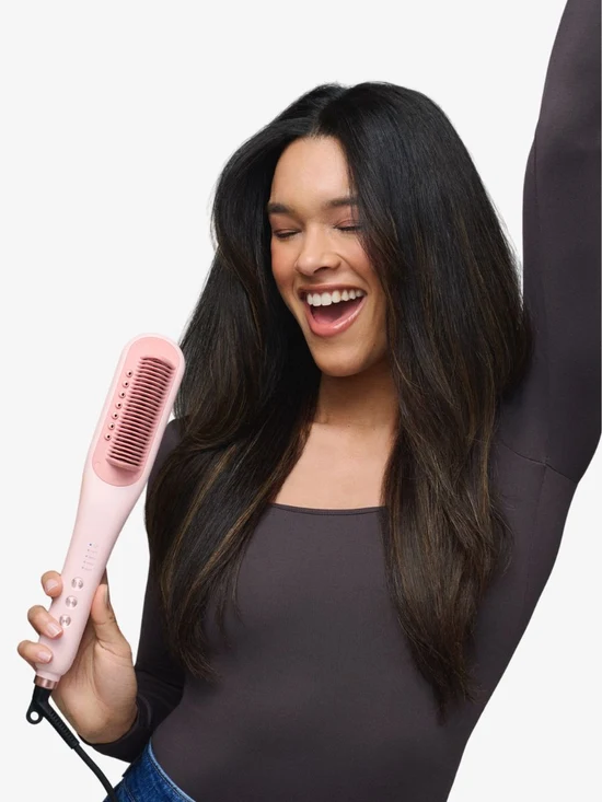 Model holding the pink Steamline Pro heated straightening brush